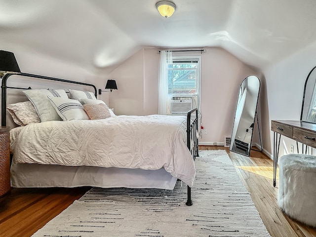 bedroom featuring vaulted ceiling, baseboards, and wood finished floors