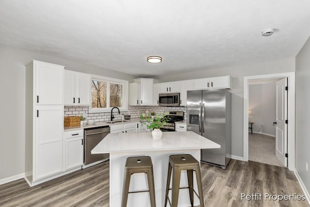 kitchen with a breakfast bar, white cabinetry, appliances with stainless steel finishes, and a sink