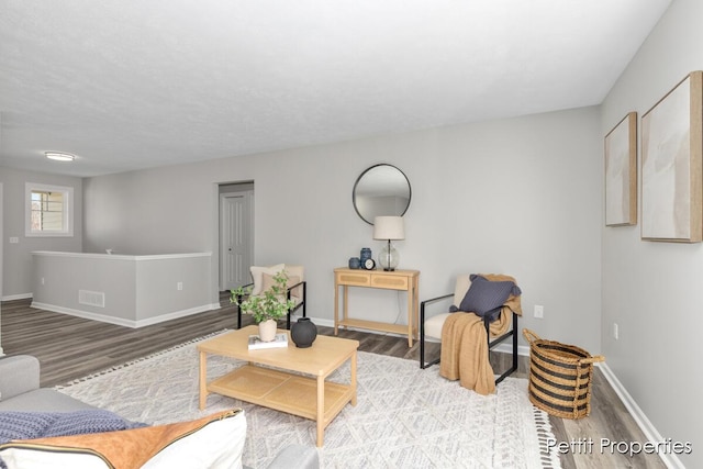 living area with visible vents, baseboards, and wood finished floors