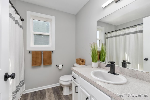 bathroom featuring vanity, toilet, wood finished floors, and baseboards