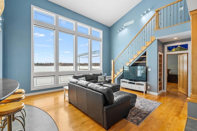 living area with wood finished floors, visible vents, and a towering ceiling