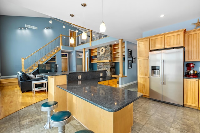 kitchen with a breakfast bar area, visible vents, a high ceiling, stainless steel fridge, and open floor plan