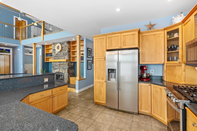 kitchen featuring light brown cabinets, recessed lighting, a fireplace, stainless steel appliances, and glass insert cabinets