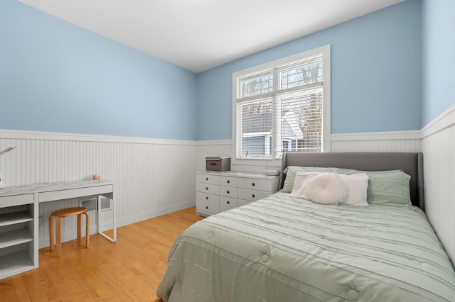 bedroom featuring light wood-style flooring and wainscoting