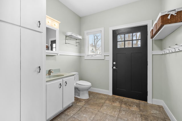 bathroom with stone finish flooring, toilet, vanity, and baseboards