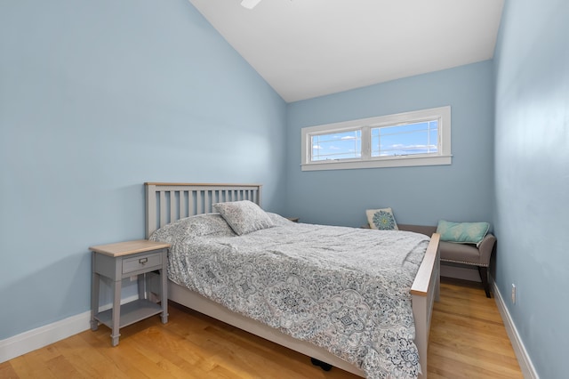 bedroom featuring baseboards, lofted ceiling, and wood finished floors