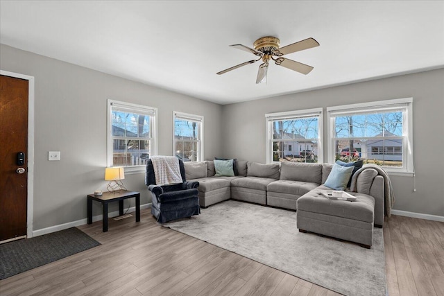 living room featuring baseboards, ceiling fan, and wood finished floors