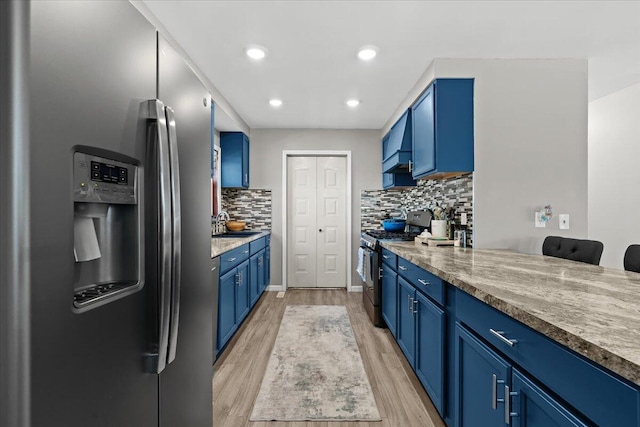 kitchen featuring blue cabinets, light wood-type flooring, recessed lighting, stainless steel appliances, and decorative backsplash