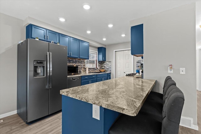 kitchen featuring a breakfast bar, a peninsula, decorative backsplash, appliances with stainless steel finishes, and blue cabinets