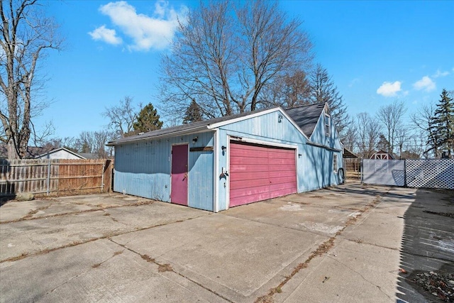 view of outdoor structure with driveway, an outdoor structure, and fence