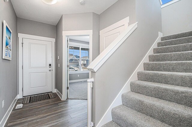 foyer featuring visible vents, stairway, wood finished floors, and baseboards