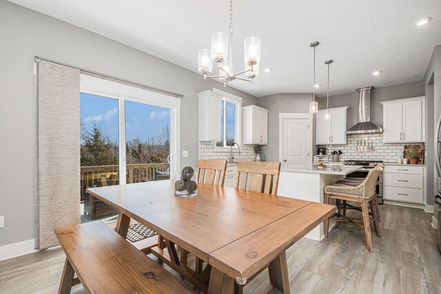 dining room with light wood finished floors, a chandelier, recessed lighting, and baseboards