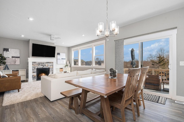 dining room with recessed lighting, wood finished floors, a fireplace, and ceiling fan with notable chandelier