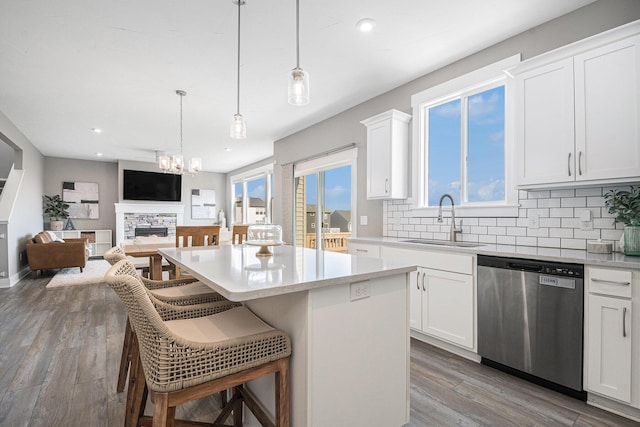 kitchen with a kitchen island, a sink, decorative backsplash, dishwasher, and a kitchen breakfast bar