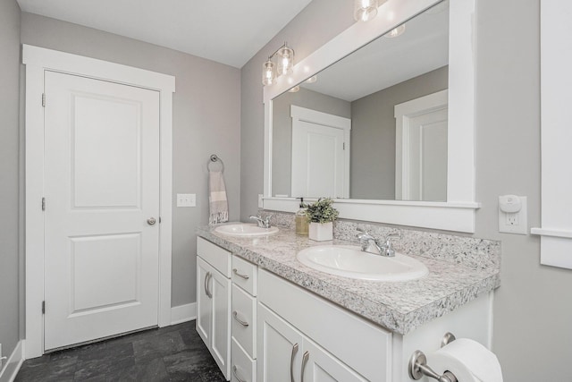 full bathroom with double vanity, baseboards, and a sink