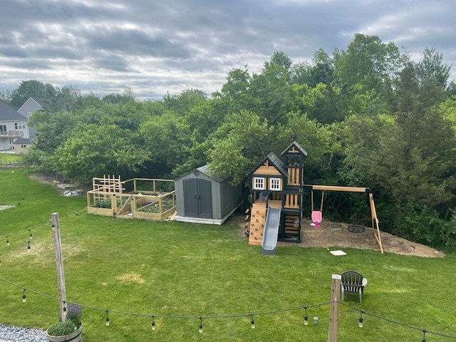 view of jungle gym with an outbuilding, a lawn, a storage shed, and a garden