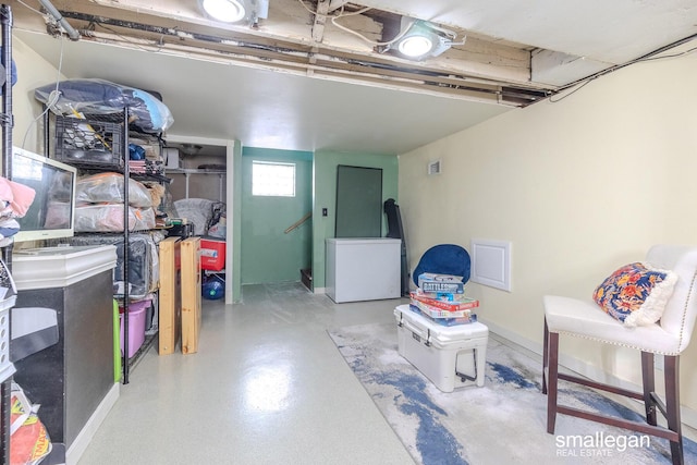 below grade area featuring visible vents, baseboards, and refrigerator