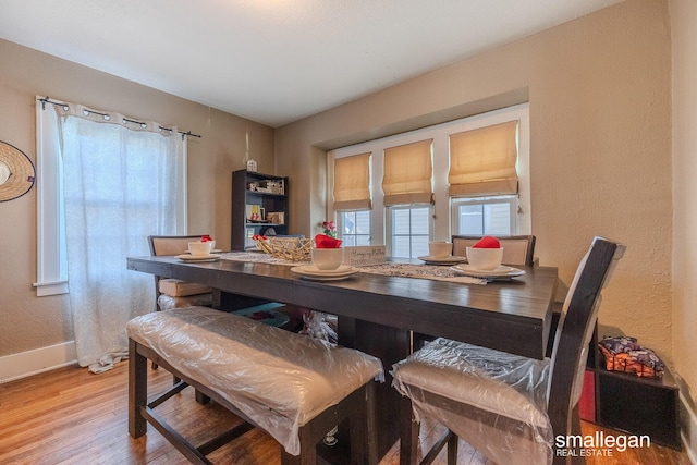 dining space with baseboards, wood finished floors, and a textured wall