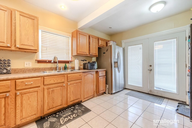 kitchen featuring light countertops, light tile patterned floors, french doors, stainless steel fridge, and a sink