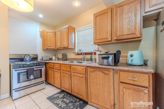 kitchen with light tile patterned floors, stainless steel range with gas cooktop, recessed lighting, a sink, and light countertops