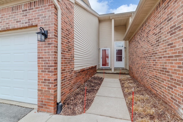 view of exterior entry featuring brick siding and a garage