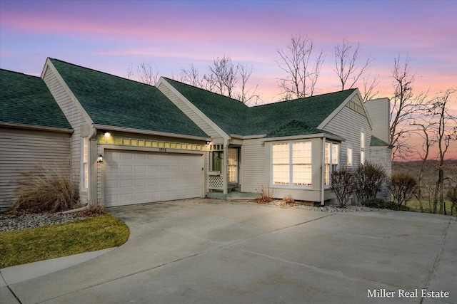 view of front of home featuring an attached garage, driveway, and a shingled roof