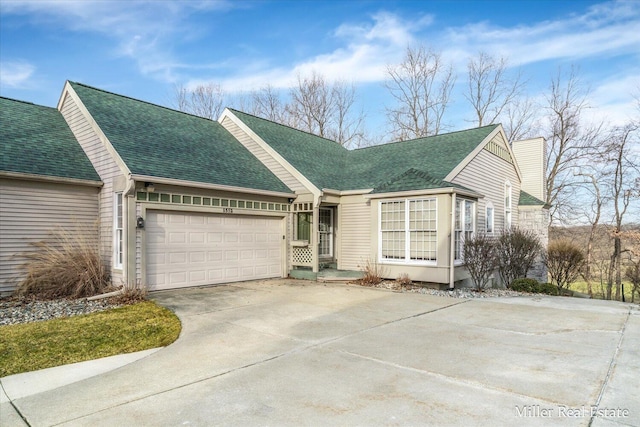 view of front of house with a garage, roof with shingles, and concrete driveway