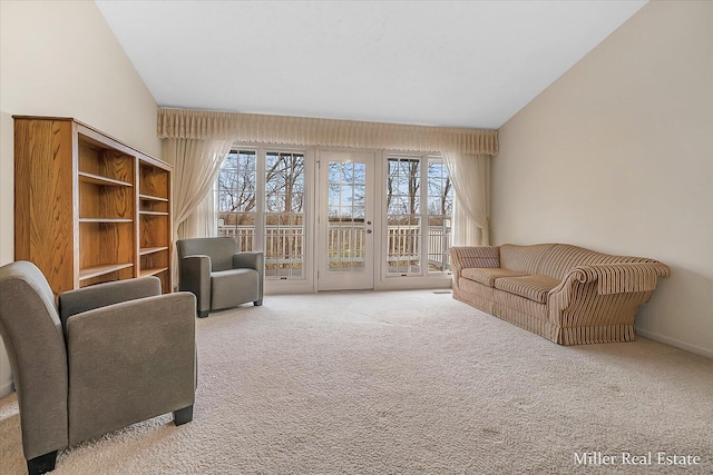 living area featuring high vaulted ceiling, a healthy amount of sunlight, french doors, and light carpet