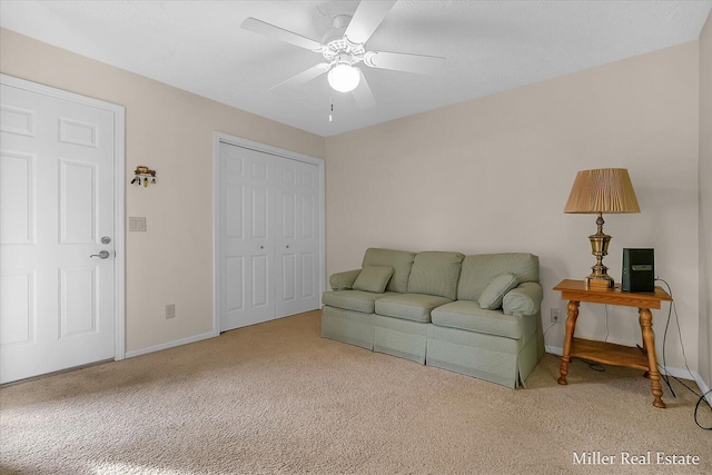 living area featuring a ceiling fan, baseboards, and carpet floors