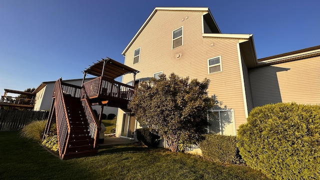 rear view of house with stairway, a lawn, and a wooden deck