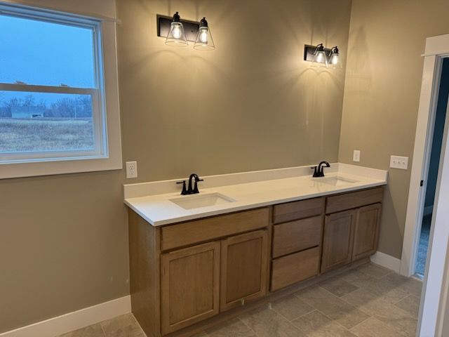 full bathroom featuring double vanity, baseboards, and a sink