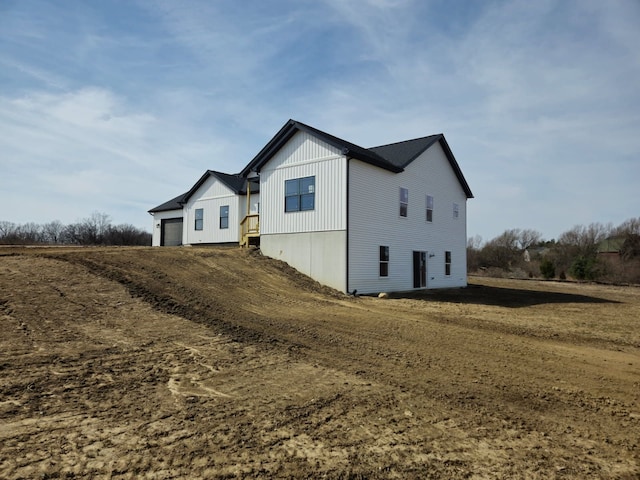 view of property exterior featuring an attached garage and dirt driveway