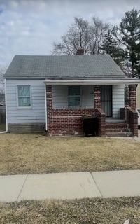 view of front of home with brick siding, covered porch, and a front yard