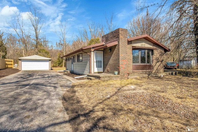 view of side of property with brick siding, a chimney, an outdoor structure, and a garage