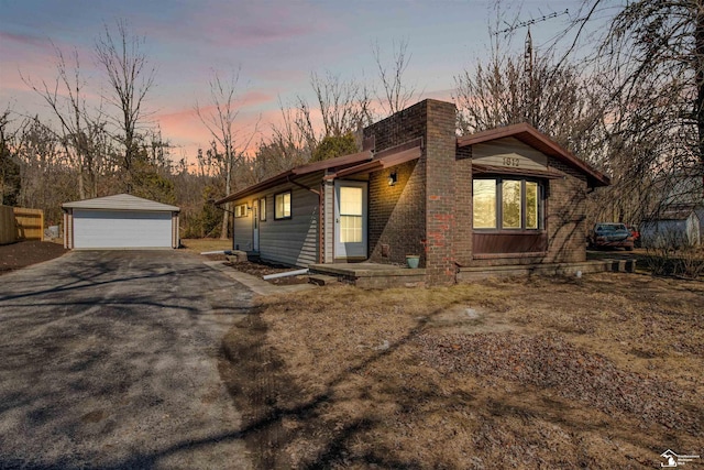 view of front of home featuring brick siding, a chimney, a detached garage, and an outdoor structure