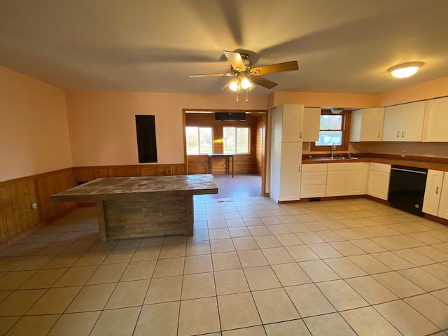 kitchen featuring light tile patterned flooring, a sink, white cabinets, wainscoting, and dishwasher