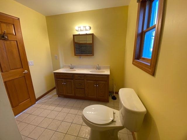 bathroom with a sink, baseboards, toilet, and double vanity