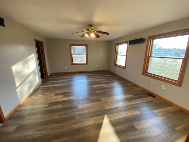 empty room with visible vents, a ceiling fan, baseboards, and dark wood-style flooring