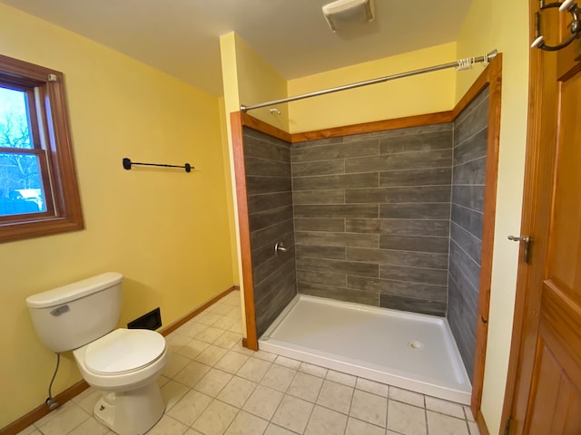 bathroom with baseboards, toilet, a shower stall, and tile patterned flooring