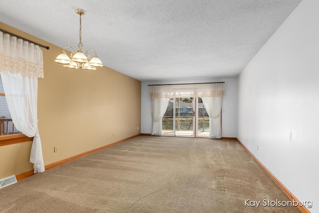 spare room featuring a notable chandelier, baseboards, visible vents, and carpet floors