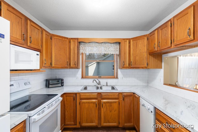 kitchen with tasteful backsplash, white appliances, light countertops, and a sink