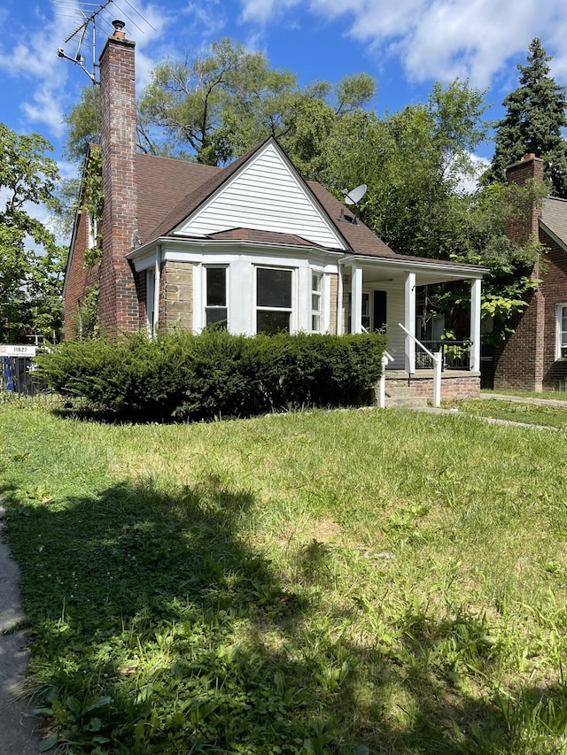 view of front of property featuring covered porch, a chimney, and a shingled roof