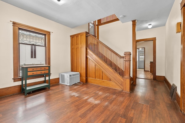 staircase featuring visible vents, an AC wall unit, wood finished floors, baseboards, and ornate columns