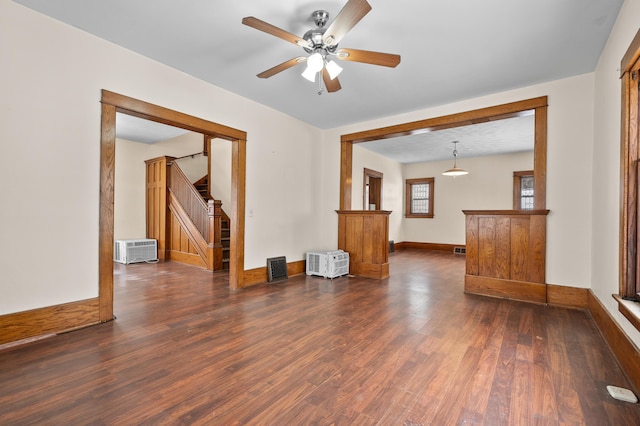 unfurnished living room with dark wood-style floors, a ceiling fan, stairs, and baseboards