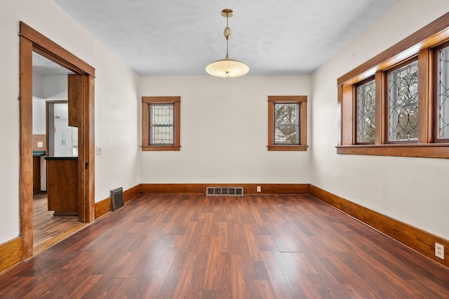 spare room with wood finished floors, visible vents, and baseboards