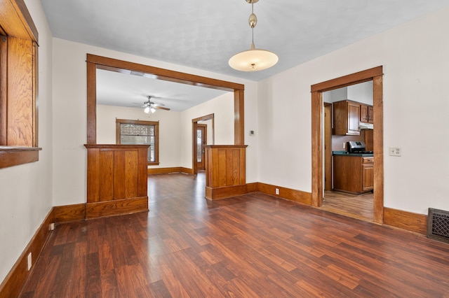 spare room featuring visible vents, baseboards, dark wood-type flooring, and ceiling fan