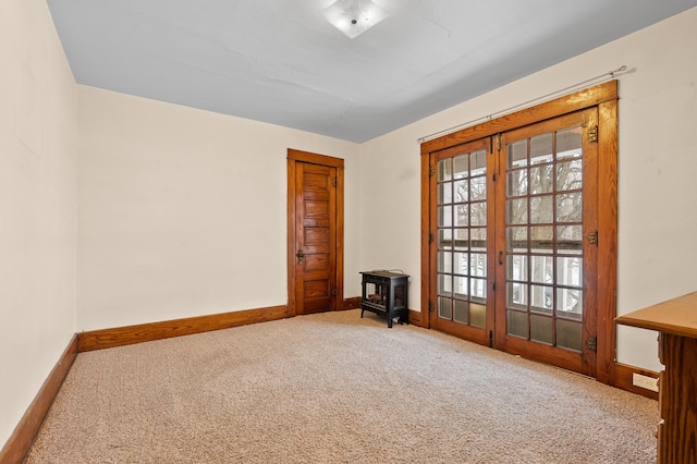 carpeted spare room with a wood stove and baseboards