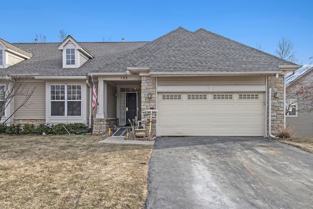 view of front facade with aphalt driveway, an attached garage, stone siding, and roof with shingles