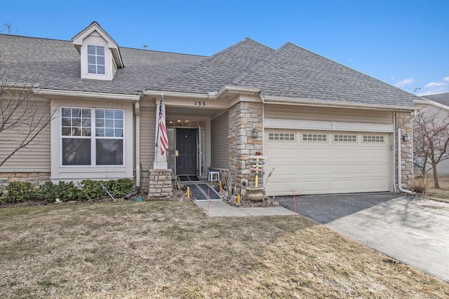 view of front of home with a front yard, roof with shingles, a garage, stone siding, and driveway