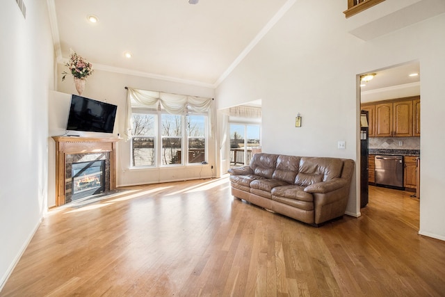 living area featuring visible vents, light wood-style flooring, a fireplace, and crown molding